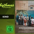 filmplakat-imschattendesorangenbaums.jpg Filmplakat mit einer Gruppe Menschen vor einer Wand mit Palmenmotiv und dem Titel des Films.