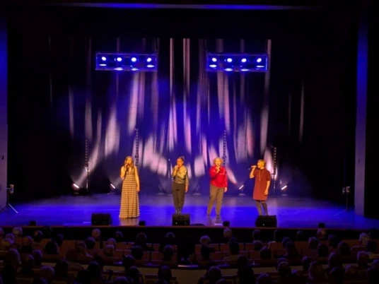 niniwe a capella Vier Sängerinnen stehen auf einer blau beleuchteten Bühne und singen vor einem sitzenden Publikum.