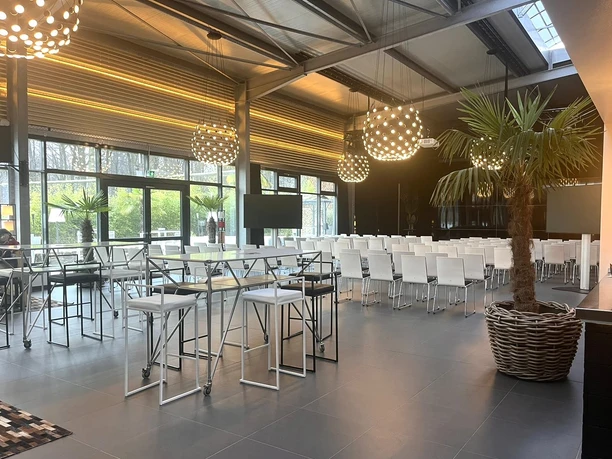 BOTANICAL by CKE - Event room Even room with conference seating and bar tables, decorated with palm trees and eye-catching pendant lights.
