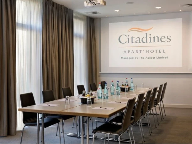Citadines City Centre Frankfurt - Conference room A conference room of the Citadines APART' HOTEL in two views. It is equipped with a long table, chairs, a projector and a projection screen.
