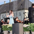 NWD Schloss Benkhausen Sängerin mit Orchester bei Open-Air-Auftritt vor hellem Schlossgebäude und Blumen