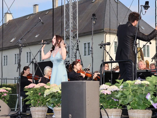 NWD Schloss Benkhausen Sängerin mit Orchester bei Open-Air-Auftritt vor hellem Schlossgebäude und Blumen
