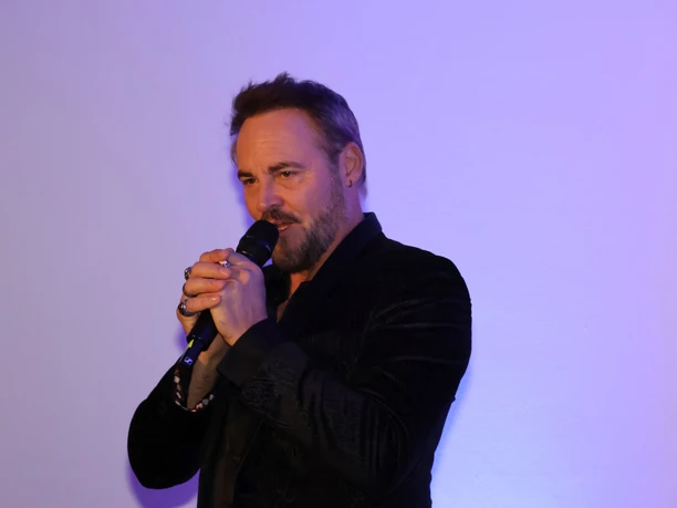 Rob Fowler Singender Mensch mit Mikrofon vor violettem Licht