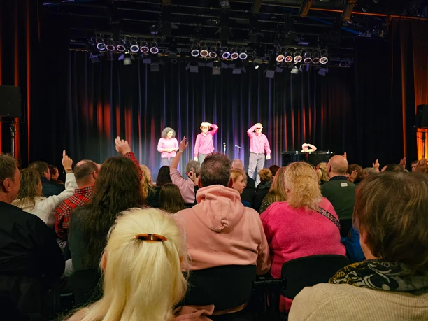 20251115_200406 (c) Tanja Mehl_Erlebnis Bremerhaven_WEB.jpg Publikum lacht und applaudiert bei einer Live-Aufführung im TiF Theater im Fischereihafen Bremerhaven.