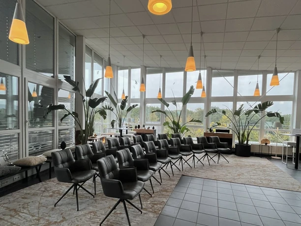 LOFT By CKE - Event room Bright, modern loft with lots of plants, rows of chairs and orange lamps.