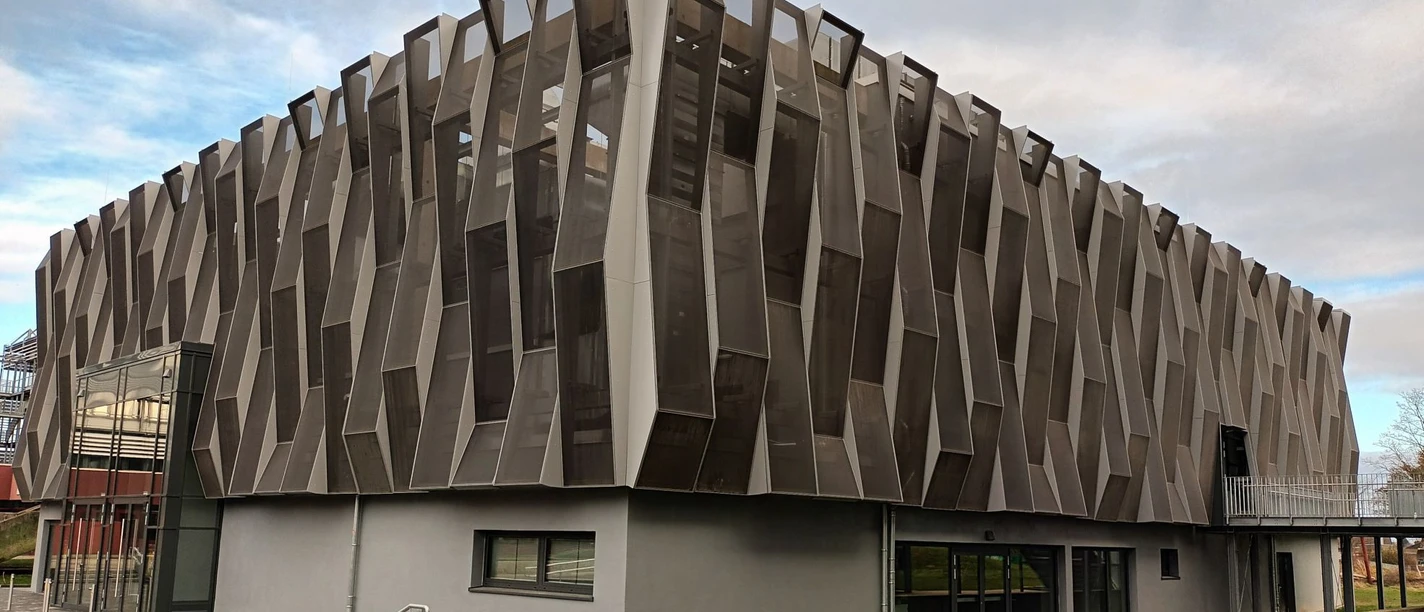 Aula_GymnasiumamFredenberg (11)_HD_16zu9.jpg Moderne Aula mit markanter, geometrischer Fassade aus Metall und Glas am Gymnasium Am Fredenberg.