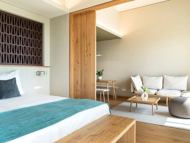 WALD.WEIT Rheingau Hotel & Retreat - Hotelzimmer Helles, modernes Hotelzimmer mit Doppelbett, Holztrennwand und gemütlicher Sitzecke.