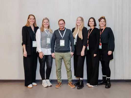 Time Change GmbH Ein Team von sechs Personen steht nebeneinander und lächelt in die Kamera.