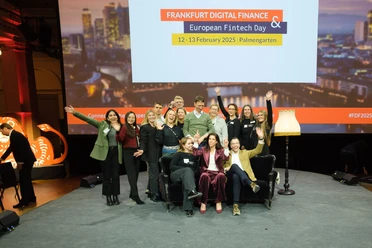 MIT Event- & Incentive-Management GmbH - large group of people A large group of people pose laughing on a stage in front of a screen with the words "FRANKFURT DIGITAL FINANCE & European Fintech Day".