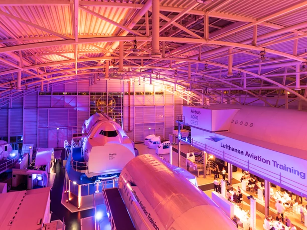 Lufthansa Aviation Training Center Frankfurt - Interior view Large warehouse with airplane parts and purple lighting.
