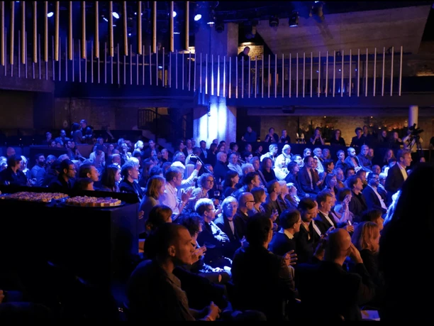 Location Rhein-Main - Event room Dark event room with many spectators in blue light following a performance or presentation.