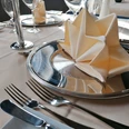 Gastronomie in Beverungen (Beispielfoto) Gedeckter Tisch mit gefalteter Stoffserviette auf Metallteller und silberfarbenem Besteck.