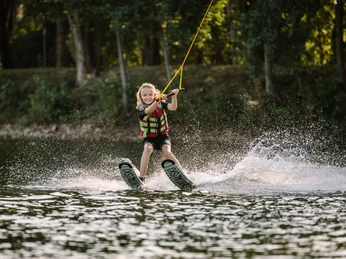 Wasserski fahren bei der Wasserskianlage Langenfeld Ein Kind auf Wasserskiern gleitet über das Wasser, in der Wasserskianlage Langenfeld