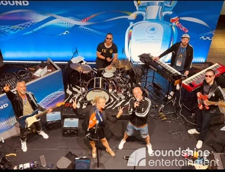 Soundshine Band, Football Lounge, Euro 2024, UEFA.jpg Band Football Lounge plays in jerseys and tracksuits with keyboards, drums and singers on a stage