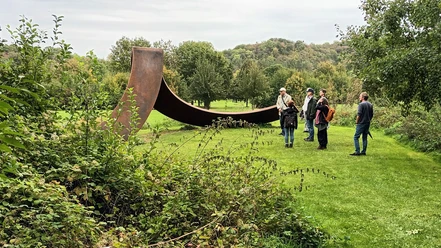 2023_Herbstspaziergang (2)_HD_16zu9.jpg Group on a guided tour in front of a large steel sculpture on the golf course in Salzgitter-Bad in the fall