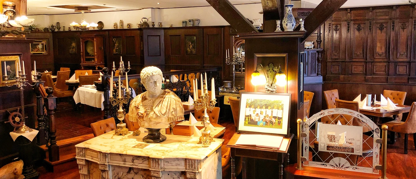 Restaurant Fiedler IMG_1386 (c) Fiedler_Erlebnis Bremerhaven.jpg Holzvertäfeltes Restaurant mit Marmordetail, römischer Büste und elegant gedeckten Tischen.