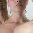 HEAL – TRANSFORMING LIFE. Der Bildausschnitt zeigt vier Personen vom Kinn zum Schlüsselbein. Auf den Hälsen sind Kreise gemalt.The picture shows four people from the chin to the collarbone. Circles are painted on the necks.