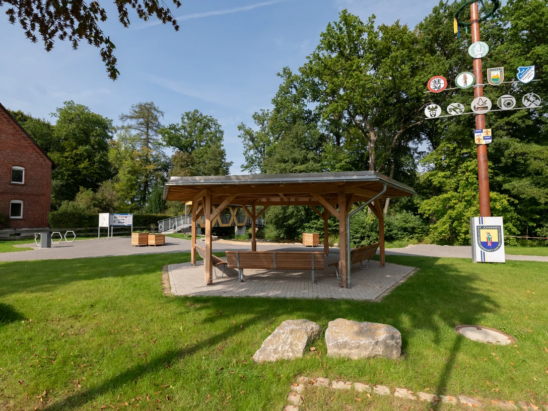 Rastplatz am Heubach in Vinsebeck Holzpavilion mit Sitzbänken, daneben ein Maibaum, Rastplatz direkt am Heubach