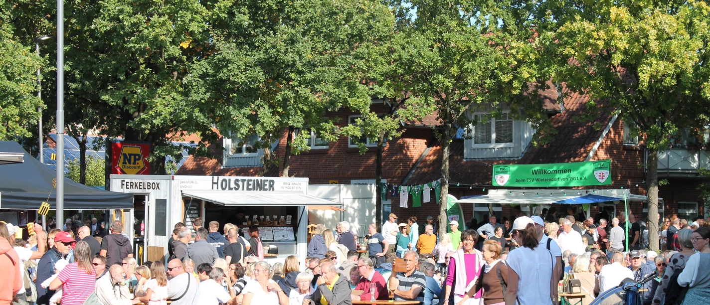 Honigfest in Wietzendorf Menschen sitzen und stehen bei sonnigem Wetter auf dem Festplatz vor der Bühne beim Honigfest in Wietzendorf.