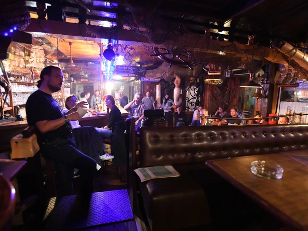 18113_051 (c) Heiko Sandelmann_Erlebnis Bremerhaven.jpg Menschen sitzen an einer Theke und hören einem Vortrag in einer maritim dekorierten Gaststätte zu.