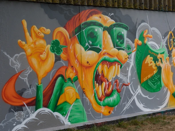 N6843 (c) Helmut Gross_Erlebnis Bremerhaven.jpg Buntes Graffiti mit grotesker Figur, großen grünen Brillen, orangener Haut und expressiver Mimik.