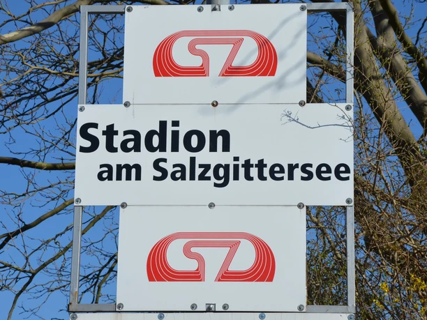 Stadion am Salzgittersee (15)_HD_16zu9.JPG Ein weißes Schild mit der schwarzen Aufschrift Stadion am Salzgittersee vor einem blauen Himmel.