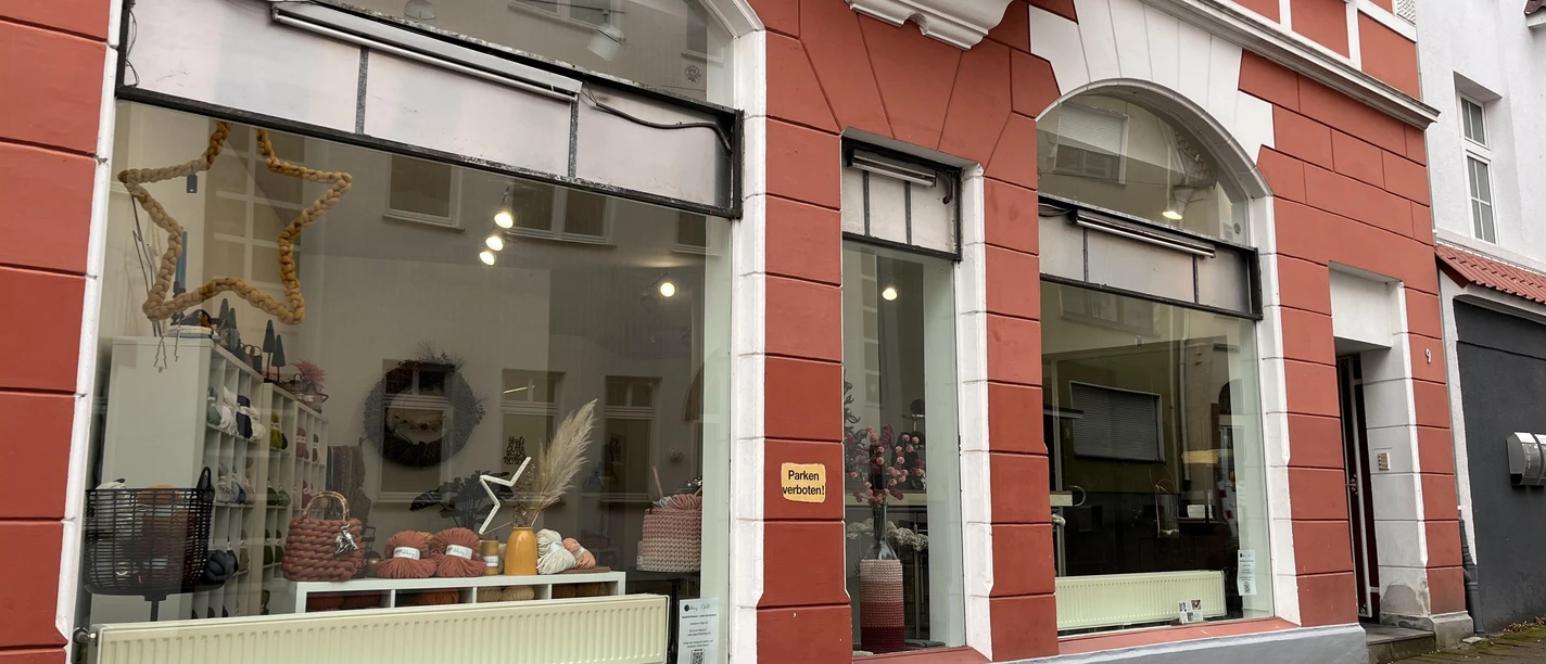 Schaufenster von Olga Voll Handmade an rot-weißer Fassade mit Wolle und Dekoration