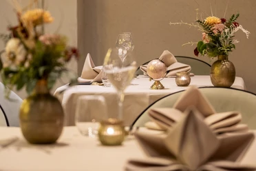 Sahila Ein elegant gedeckter Tisch mit goldenen Vasen und frischen Blumen.