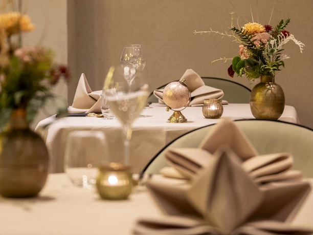 Sahila An elegantly laid table with golden vases and fresh flowers.