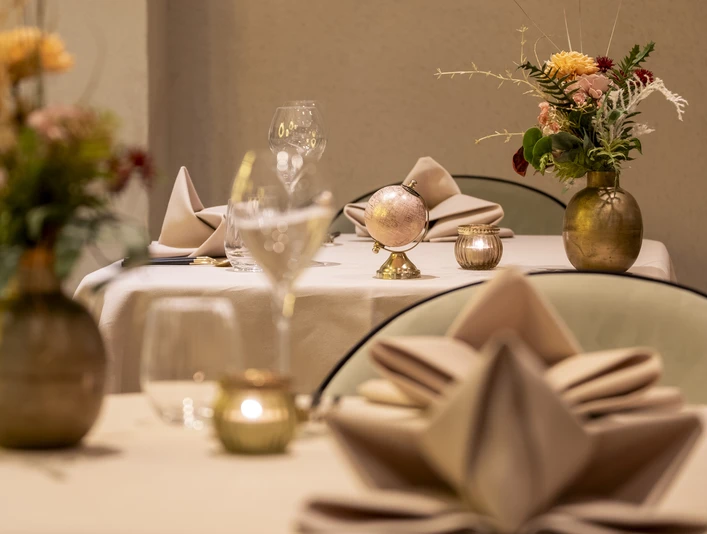 Sahila Ein elegant gedeckter Tisch mit goldenen Vasen und frischen Blumen.An elegantly laid table with golden vases and fresh flowers.