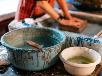 Blaudruck Workshop Person beim Blaudruck, arbeitet mit Farbschalen und Stoff an einem Handwerkstisch in Einbeck.