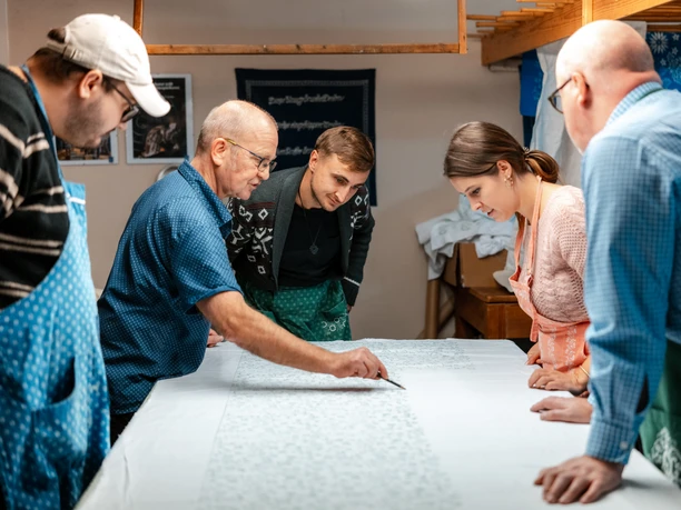 Blaudruck Workshop Menschen arbeiten konzentriert an einem langen Stofftisch im Blaudruck-Workshop in Einbeck.