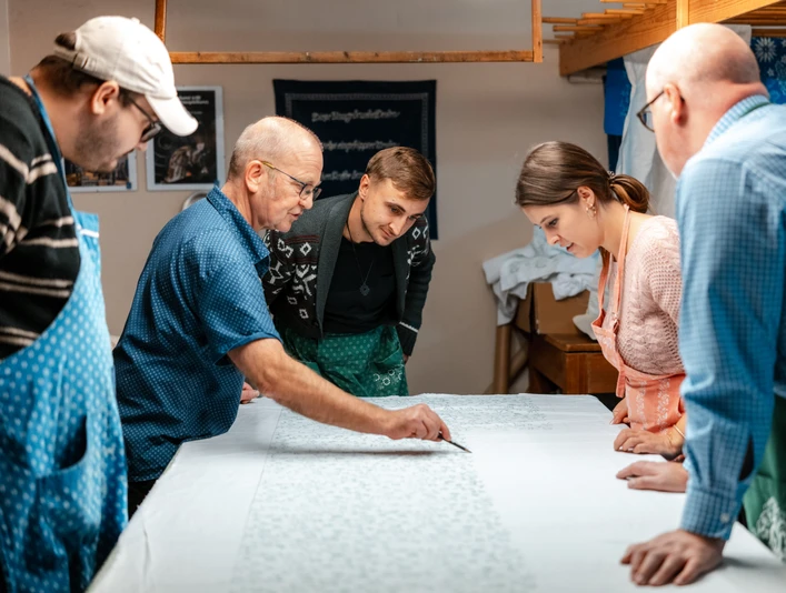 Blaudruck Workshop Menschen arbeiten konzentriert an einem langen Stofftisch im Blaudruck-Workshop in Einbeck.