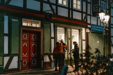 Blaudruck Workshop Menschen stehen abends vor dem Einbecker Blaudruckhaus mit Fachwerkfassade und Laternenlicht.