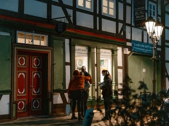 Blaudruck Workshop Menschen stehen abends vor dem Einbecker Blaudruckhaus mit Fachwerkfassade und Laternenlicht.