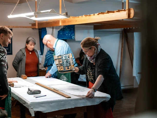 Mehrere Personen arbeiten konzentriert im Blaudruck-Workshop an einem langen Arbeitstisch.