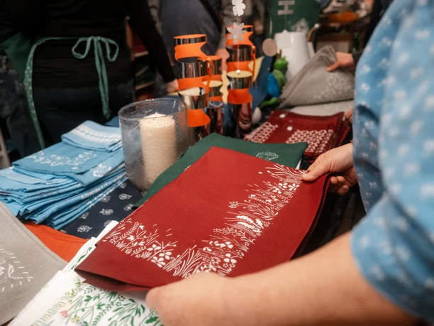 Blaudruck Workshop People at the blue printing workshop fold colorful printed fabrics with floral patterns in Einbeck