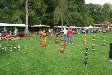 Töpfermarkt.JPG Besucherinnen und Besucher schlendern über einen Töpfermarkt mit bunten Keramikkunstwerken im Freien.