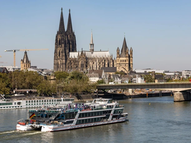 Panoramafahrt auf dem Rhein Ausflugsboot auf dem Rhein vor Kölner Dom und Altstadt bei klarem Tageslicht.