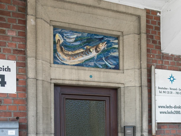 Halle XIV M3383 (c) Helmut Gross_Erlebnis Bremerhaven.jpg Eingangstür aus dunklem Holz in Backsteinfassade mit Fischmosaik über dem Türrahmen.
