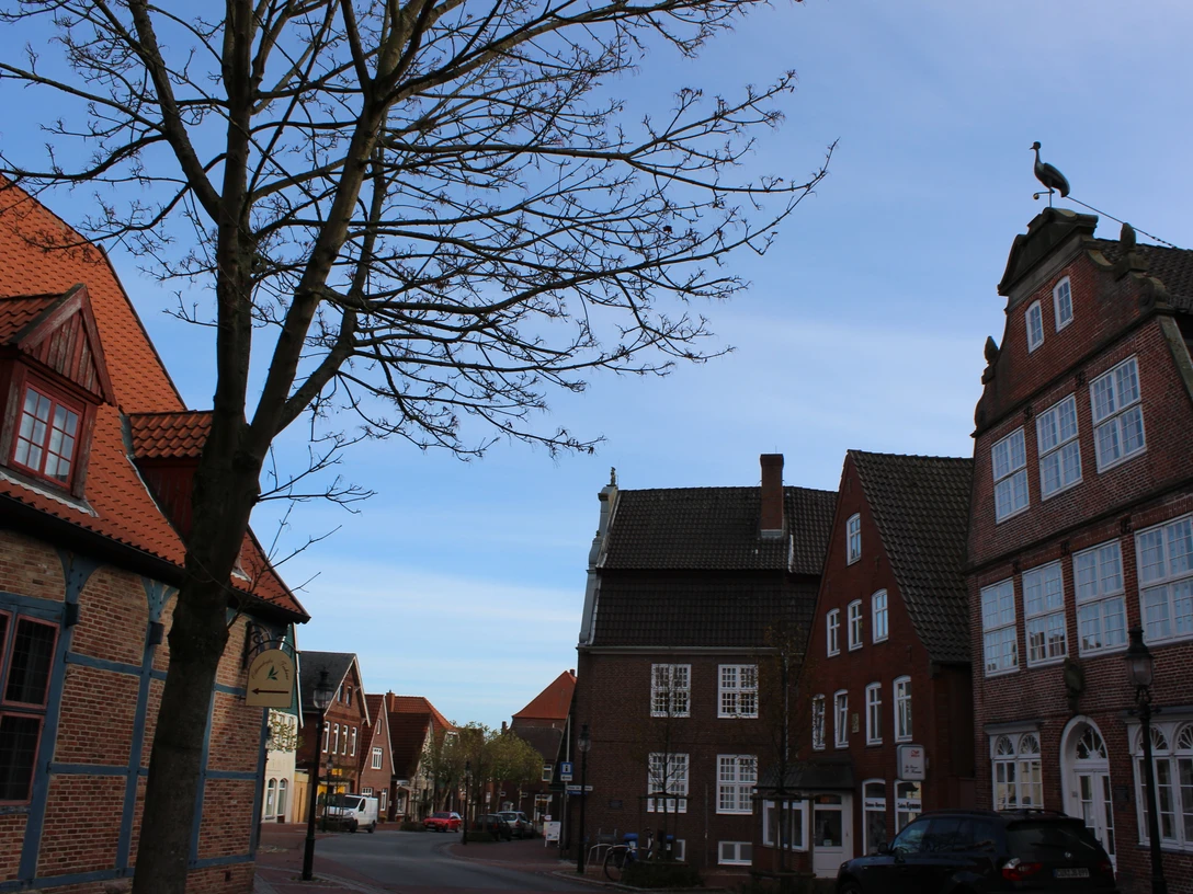 Kranichhaus Otterndorf © Stadt Otterndorf Straße mit alten Backsteinhäusern in Otterndorf. Auf einem Haus steht eine Storchenfigur.Street with old brick houses in Otterndorf. There is a stork figure on one of the houses.Gade med gamle murstenshuse i Otterndorf. Der er en storkefigur på et af husene.Straat met oude bakstenen huizen in Otterndorf. Op een van de huizen staat een ooievaarsfiguur.