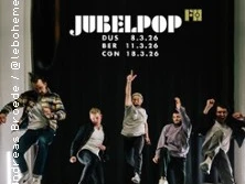 Eine Band springt energiegeladen vor schwarzem Vorhang, darüber stehen Tourdaten.