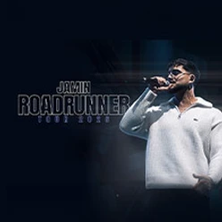 Sänger auf dunkler Bühne mit Mikrofon neben Schriftzug zur Roadrunner Tour 2026.