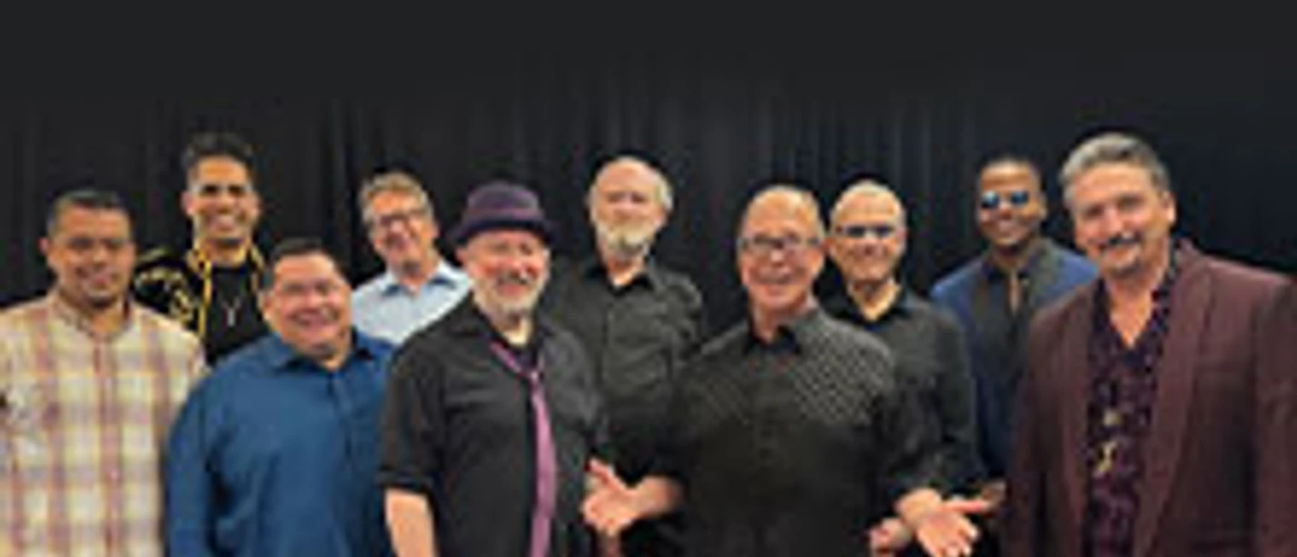 Eine Gruppe von elf Personen steht vor dunklem Hintergrund unter dem Schriftzug Tower of Power.