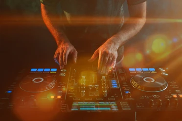 Closeup of a DJ working under the lights against a dark background in a studio Closeup of a DJ working under the lights against a dark background in a studio