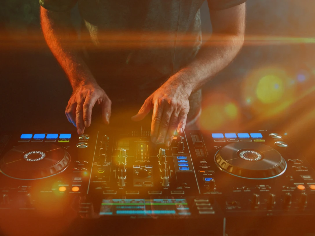 Closeup of a DJ working under the lights against a dark background in a studio Closeup of a DJ working under the lights against a dark background in a studio