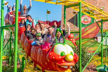 Karls Erlebnishof - Ausflugsziele in der Region Leipzig Auf dem Bild ist die Raupenbahn im Freizeitpark Karls Erlebnisdorf zu sehen. Mehrere Kinder sitzen in den bunten Waggons der kleinen Achterbahn und jubeln vor Freude.