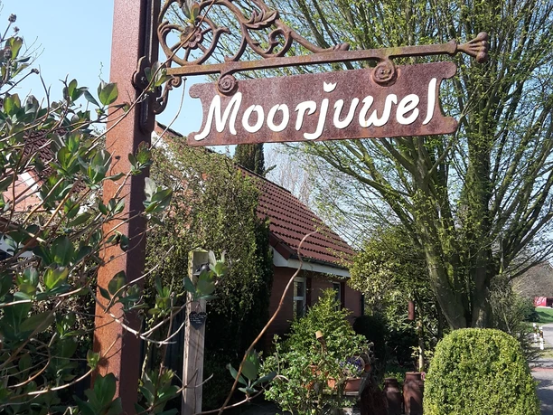 Gartenschild auf dem Moorjuwel steht, im Hintergrund Baum