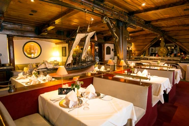 Holzvertäfeltes Fischrestaurant mit maritimem Dekor, weißen Tischdecken und eleganter Atmosphäre.