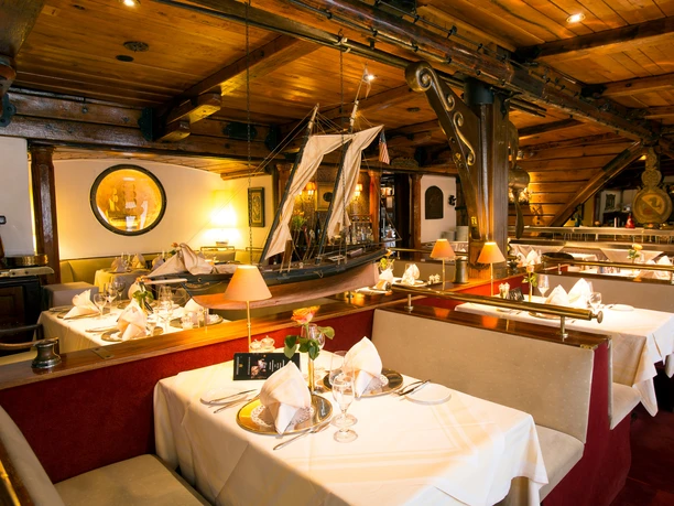 Restaurant Capt (c) Natusch.jpg Holzvertäfeltes Fischrestaurant mit maritimem Dekor, weißen Tischdecken und eleganter Atmosphäre.